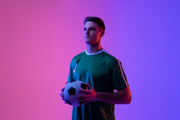 Caucasian male soccer player with football over neon pink lighting © vectorfusionart