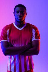 Portrait of african american male soccer player over neon pink lighting