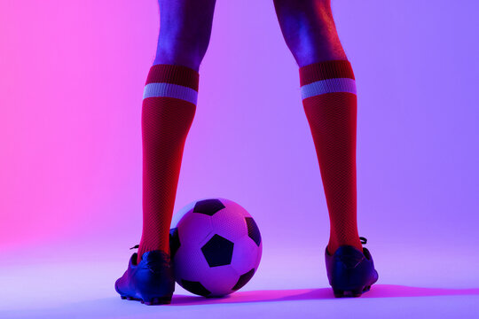 African american male soccer player with football over neon pink lighting - Powered by Adobe