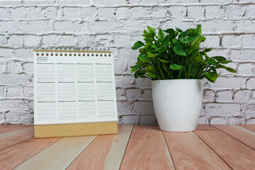 2022 calendar with potted plant on wooden desk. New year concept.