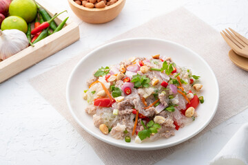 Spicy Glass Noodle Salad with Minced Pork (Yum woon sen) is a type of Thai salad made with clear bean vermicelli and meat in white plate