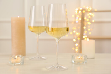 Glasses of wine and candles on wooden table