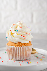 Delicious vanilla cupcakes with cream cheese and sugar candy on a gray background. Dessert for birthday. selective focus, copy space.