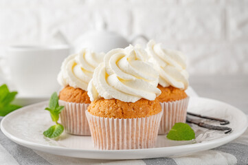 Delicious vanilla cupcakes with cream cheese and sugar candy on a gray background. Dessert for birthday. selective focus, copy space.