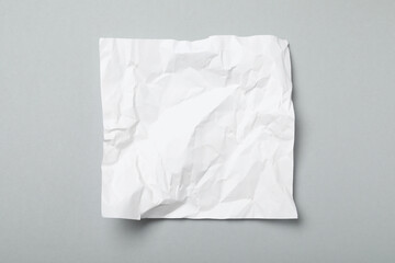 Obraz premium Sheet of white crumpled paper on grey background, top view