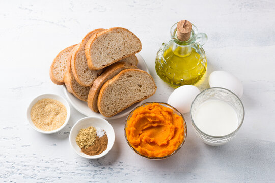 Ingredients For Spicy Pumpkin Toast: Pumpkin Puree, Bread, Eggs, Milk, Vegetable Oil, Brown Sugar And Spices - Ginger, Cinnamon, Salt. Cooking Delicious Homemade Food On A Light Gray Background