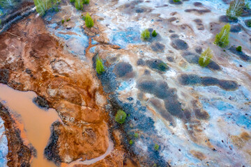 Polluted rusty dirty creek. Nature pollution concept. Water with pieces of ice around the edges. Top view of yellow stream. Aerial view from drone