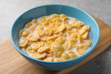 Tasty cornflakes with milk in bowl on table, closeup