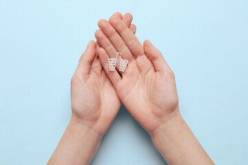 Woman holding anti-snoring device for nose on turquoise background, top view