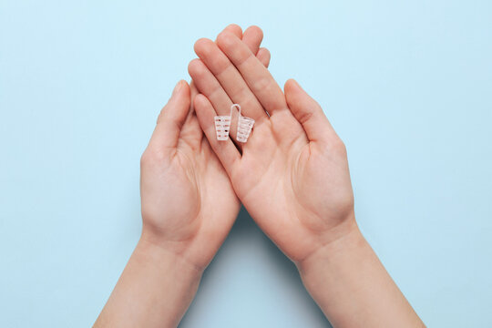 Woman holding anti-snoring device for nose on turquoise background, top view