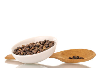Dry fragrant black pepper in a white saucer with a wooden spoon, close-up, isolated on a white background.