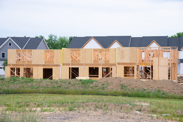 A residential house construction project showing plywood roof and dormer sheathing and oriented strand board or chipboard sheathing on the exterior walls