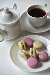Porcelain teapot with a cup of tea and pasta on a white background.