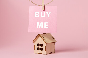 Changes in real estate prices. The concept of real estate services. Bargain home purchase. Small wooden house on a pink background - obrazy, fototapety, plakaty