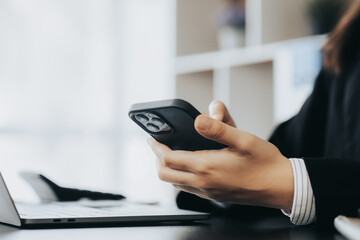 Businesswoman looking at financial information from a mobile phone, she is checking company financial documents, she is a female executive of a startup company. Concept of financial management.