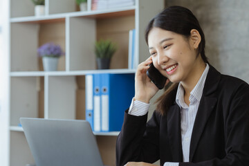 Asian woman talking on the phone, she is a salesperson in a startup company, she is calling customers to sell products and promotions. Concept of selling products through telephone channels.