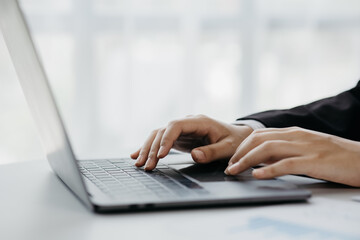Close-up business man working in a private room, He is typing on a laptop keyboard, He uses a messenger to chat with a partner. Concept of using technology in communication.