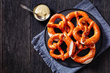 pretzels in the form of knot with cheese sauce - obrazy, fototapety, plakaty