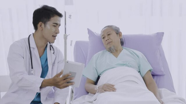 Doctor holding a tablet and talking to the patient. Older nice man and young doctor at room.