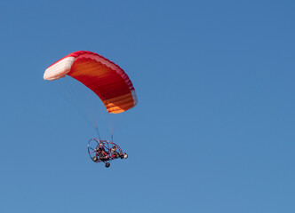 Aircraft with a red parachute and an engine controlled by the pilot.copy space