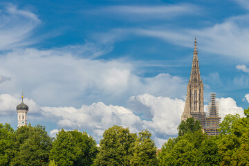 The tower of the Ulm Minster (Ulmer Münster) and the Holy Trinity Church (Dreifaltigkeitskirche) in Ulm, Germany. Bright blue sky, green trees, sunny summer weather