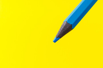 Colored pencil close-up with selective focus on the stylus and a blurred yellow background. Copy...