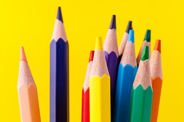 Colored pencils close-up with selective focus on the stylus and a blurred yellow background