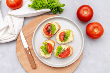 Bruschetta sandwich bread toast with soft white cheese ricotta,fresh tomatoes,basil greenery on a wooden cutting board.Tasty healthy vegetarian food,Italian cuisine appetizer. top view flat lay