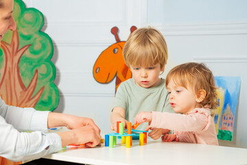 Obraz na płótnie Canvas Woman and two little kindergarten kids build tower