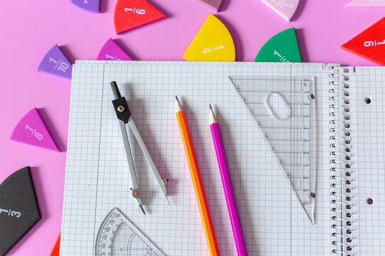 Back to school background. Open notepad, fractions, chart, pencils on a pastel pink background. Close up parts of yellow math fractions. Back to school, fun study, mathematics