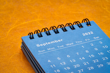 September 2022 - spiral desktop calendar against bright colorful handmade paper, time and business concept