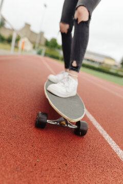 detail shot teenage girl riding skate board on a sports field