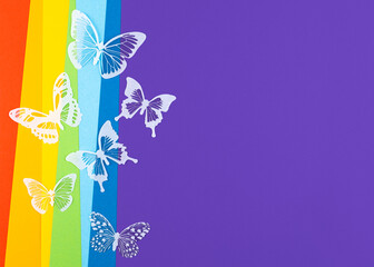 Rainbow paper background with white butterflies. Zero discrimination day concept.