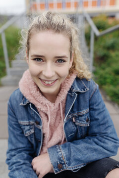 Young teenage girl sitting on stairs looking at camera laughing