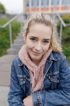 Young teenage girl sitting on stairs looking at camera smiling