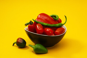 Fresh peppers and cherry tomatoes on an orange background. Close-up