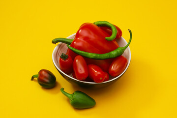 Fresh peppers and cherry tomatoes on an orange background. Close-up