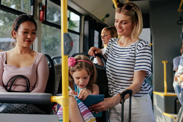 Girl doing homework with mom in public transport