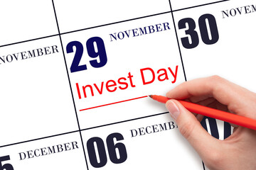 Hand drawing red line and writing the text Invest Day on calendar date November 29. Business and financial concept.