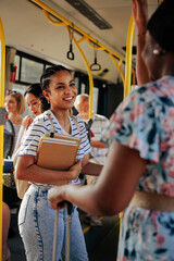 Student with books in arms talking to passenger on bus