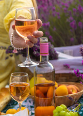 A woman drinks wine in a lavender field. Selective focus.