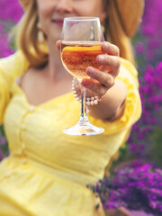 A woman drinks wine in a lavender field. Selective focus.