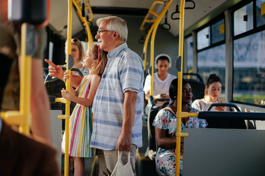 Senior man and granddaughter in public transport