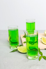 Sweet refreshing mint liqueur, with ice and mint leaves on table background, Shots with lime slice and mint flat lay