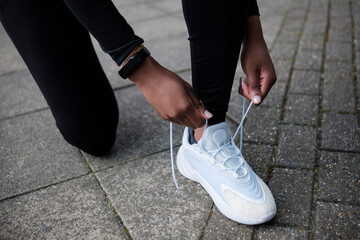 Close up of female black hands tying lace sport shoes.