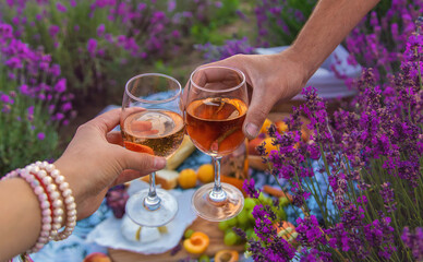 A woman and a man drink wine in a lavender field. Selective focus.