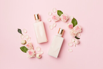 Cosmetic bottles with rose flower on color background, top view