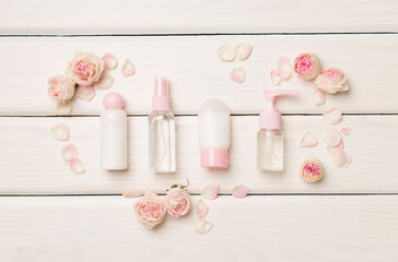 Set of small cosmetic bottles on wooden background, top view