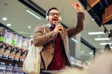 Cheerful man using technology and shopping in grocery