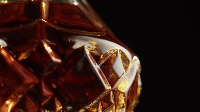 Brandy or whiskey in decanter close-up. Luxury cognac on black background. Alcohol amber drink, drinking rum, liqour beverage in glass.